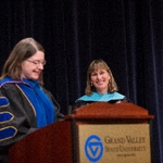 Faculty member smiles as she listens to a speech given
